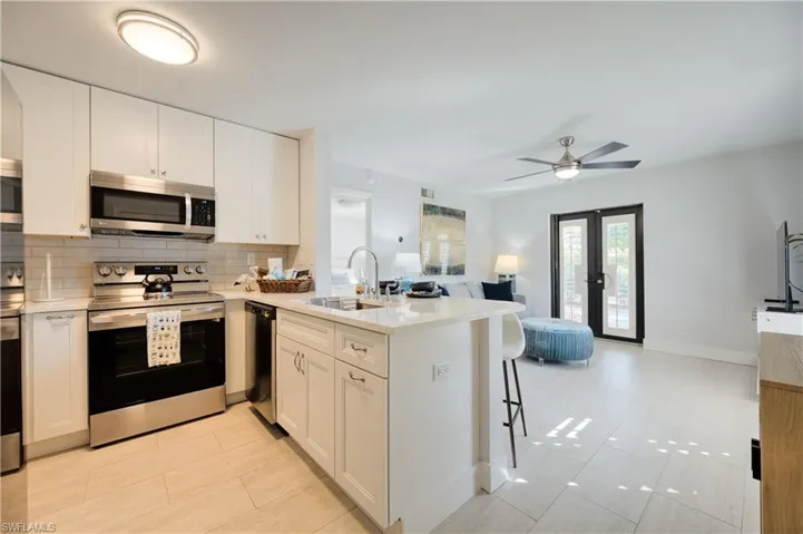 Kitchen featuring stainless steel appliances, kitchen peninsula, and white cabinets