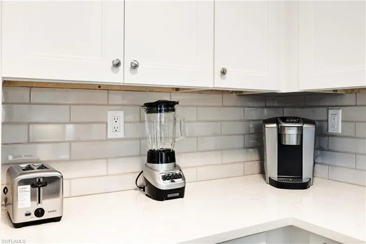 Interior details featuring light stone counters, white cabinets, and backsplash