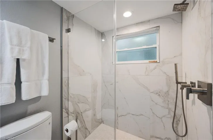 Bathroom featuring tiled shower and toilet