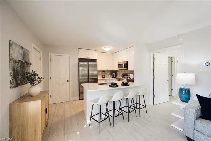 Kitchen featuring sink, a breakfast bar area, white cabinetry, tasteful backsplash, and appliances with stainless steel finishes