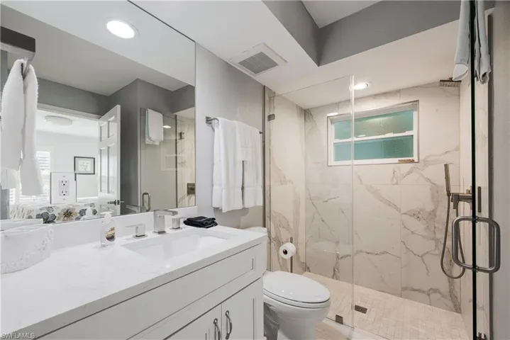 Bathroom featuring a healthy amount of sunlight, vanity, toilet, and an enclosed shower