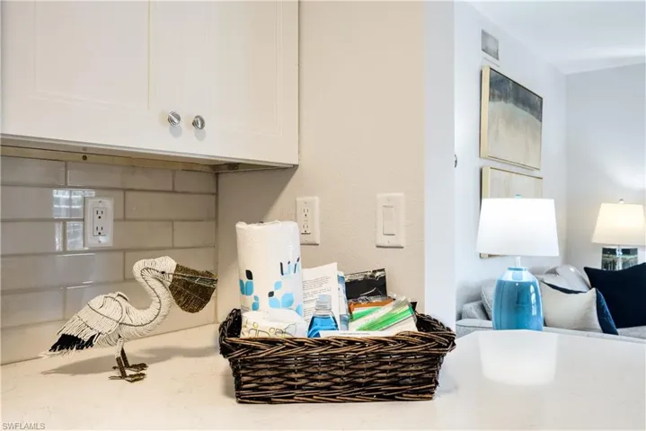 Details with white cabinetry, light stone counters, and backsplash