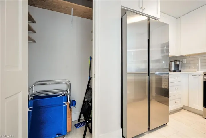Kitchen featuring white cabinetry, decorative backsplash, and stainless steel fridge