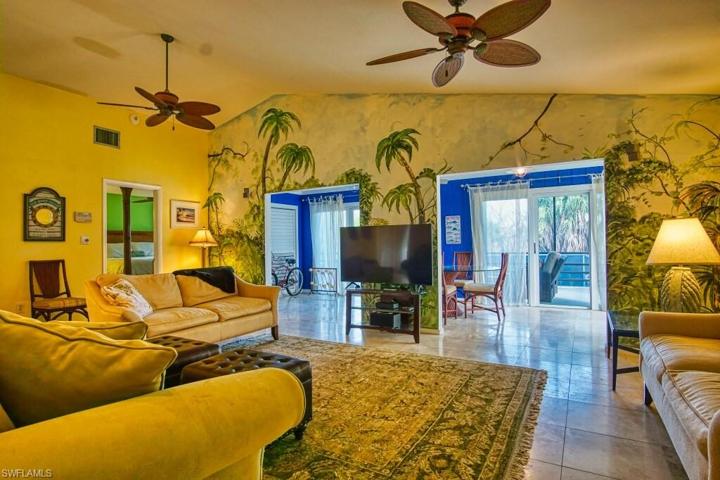 Main living area featuring a vaulted ceiling, custom hand painted mural, decorative ceiling fans, and natural stone flooring.