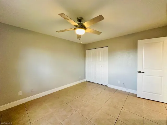 Unfurnished bedroom with a closet, ceiling fan, and light tile patterned flooring