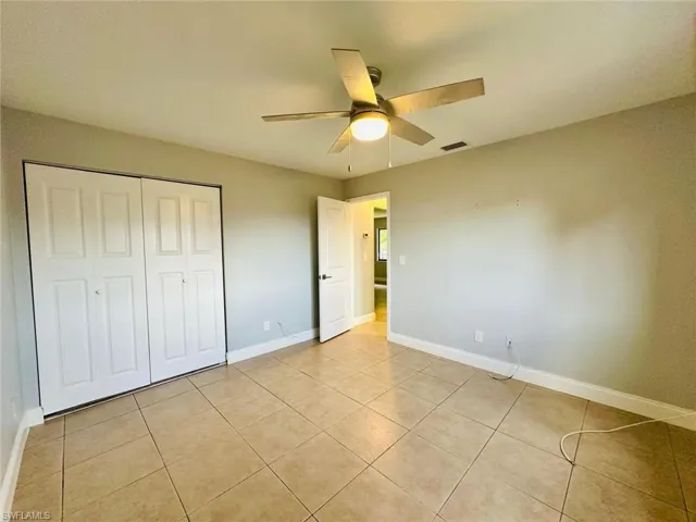Unfurnished bedroom featuring a closet, a ceiling fan, and light tile patterned floors