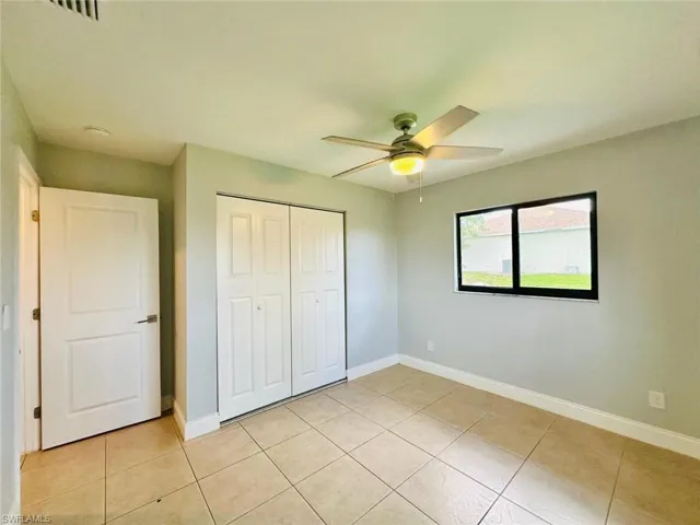 Unfurnished bedroom featuring a closet, a ceiling fan, and light tile patterned flooring