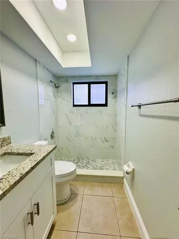 Bathroom featuring vanity, a marble finish shower, and light tile patterned flooring