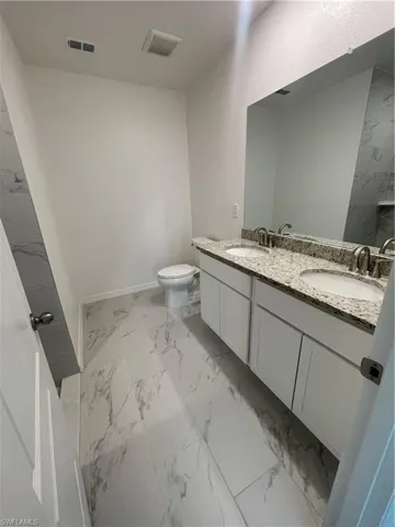 Bathroom featuring dual vanity, tile patterned floors, and toilet