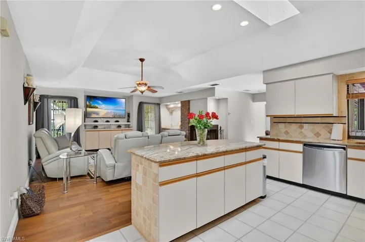 Dual tone kitchen featuring a kitchen island, backsplash, two tone cabinets, stainless steel dishwasher, and ceiling fan