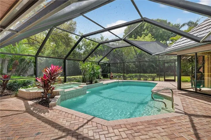 Relaxing pool / spa featuring a sunroom, a patio, and glass enclosure