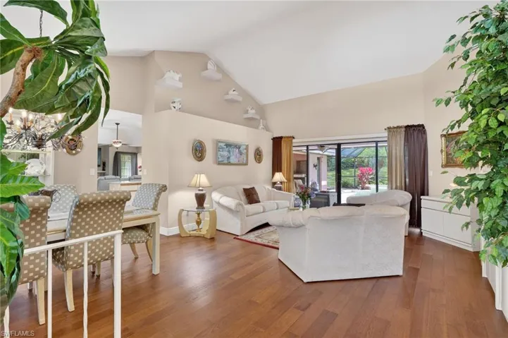 Living area with lofted ceiling, dark wood-style floors, and a ceiling fan