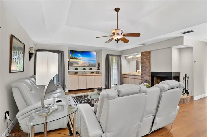 Living room with a ceiling fan, a fireplace, and light wood-style flooring