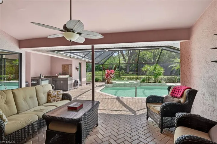 Combined pool / hot tub featuring a sunroom, a patio, a lanai, and an outdoor kitchen and area to lounge