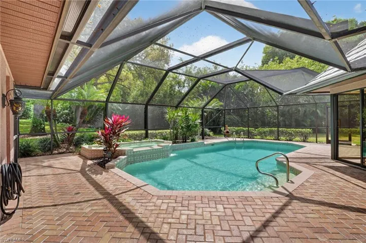 Integrated pool / hot tub featuring a patio, a sunroom, and glass enclosure