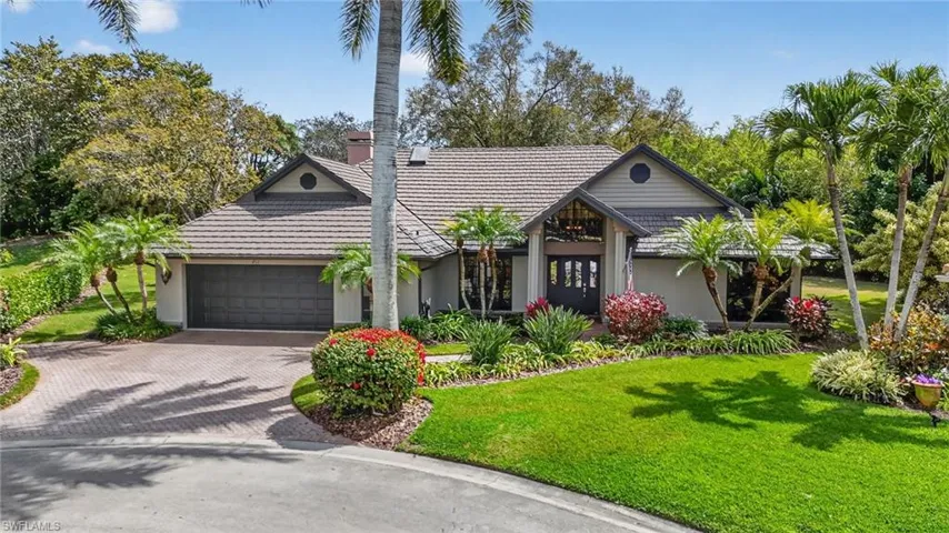 View of front of property with a front lawn, decorative driveway, and a garage