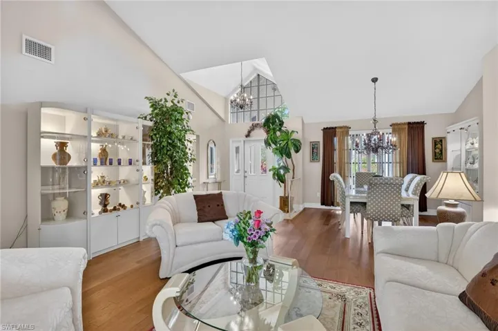 Living room featuring suspended lighting, lofted ceiling, and wood finished floors