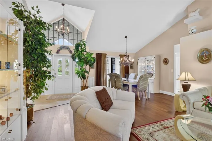 Living room with suspended lighting, hardwood / wood-style flooring, and lofted ceiling