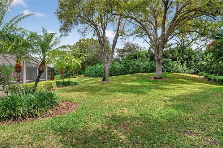 View of green lawn featuring a sunroom and a lanai