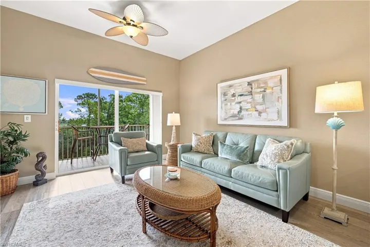 Sliding glass doors opening to a private balcony, wood-finish flooring, a ceiling fan, and neutral wall tones