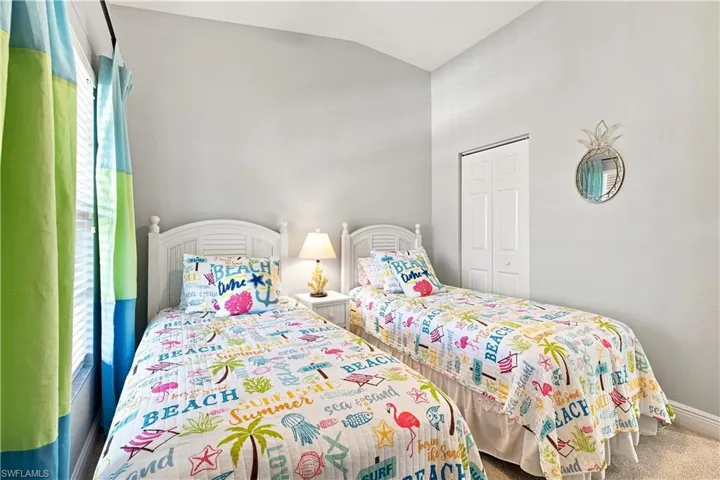 Vaulted ceiling with bright walls, two single beds with white headboards, and bi-fold closet doors