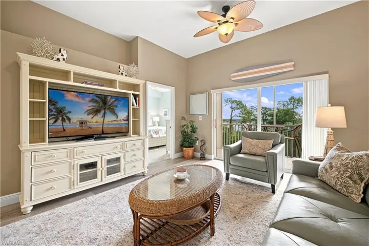Tray ceiling with a ceiling fan, sliding glass doors to the balcony, and a built-in media console