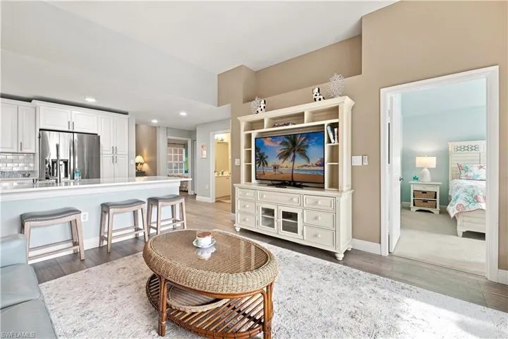 White shaker cabinetry, stainless steel refrigerator, white subway tile backsplash, and light wood-finish flooring