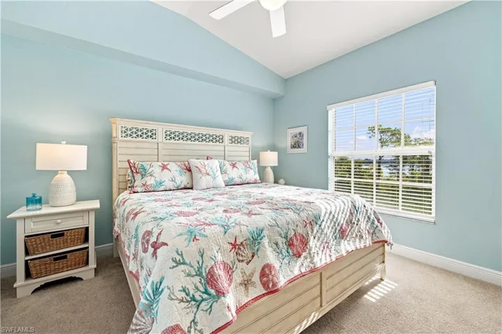 Vaulted ceiling with a ceiling fan, window with horizontal blinds, neutral carpet, and light-toned walls