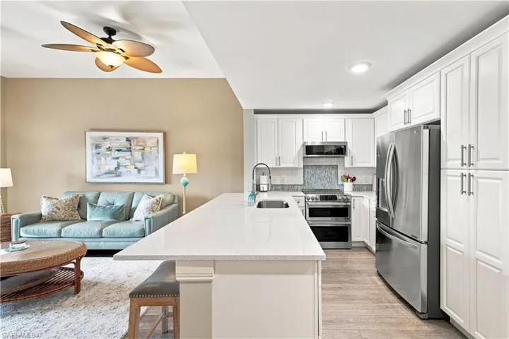 Kitchen featuring white cabinetry, stainless steel appliances, a white solid surface countertop, and wood-finish flooring