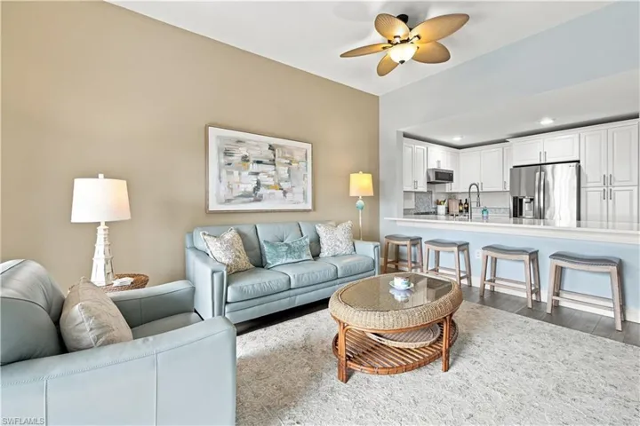 Open-concept living space featuring a ceiling fan, wood-finish flooring, and a kitchen pass-through with counter seating