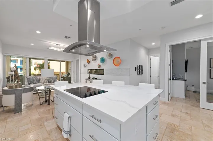 Kitchen with white cabinetry, island range hood, a kitchen island, black electric cooktop, and light stone countertops