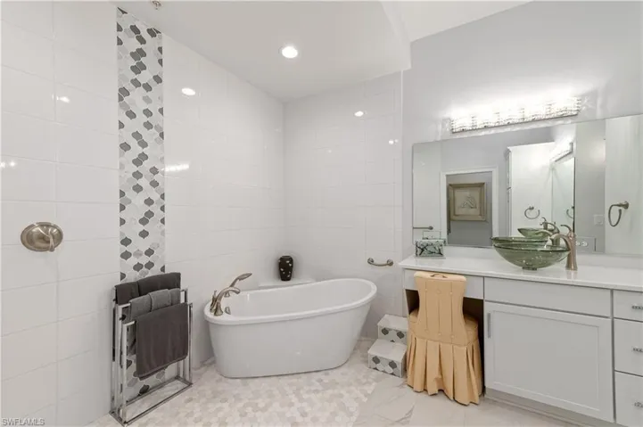 Bathroom featuring tile walls, vanity, and a bathing tub