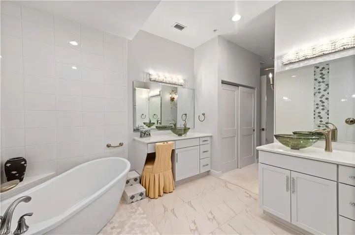 Bathroom featuring a tub to relax in, tile walls, and vanity