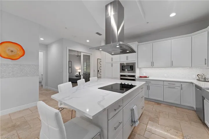 Kitchen featuring island range hood, appliances with stainless steel finishes, a kitchen bar, and a kitchen island