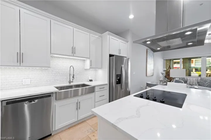 Kitchen featuring white cabinetry, island range hood, appliances with stainless steel finishes, and light stone counters