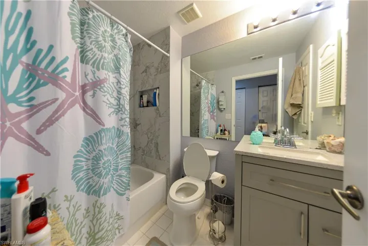 Full bathroom with vanity, tile patterned floors, toilet, and shower / tub combo with curtain