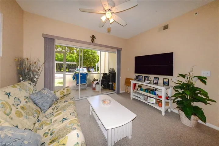 Carpeted living room featuring vaulted ceiling and ceiling fan