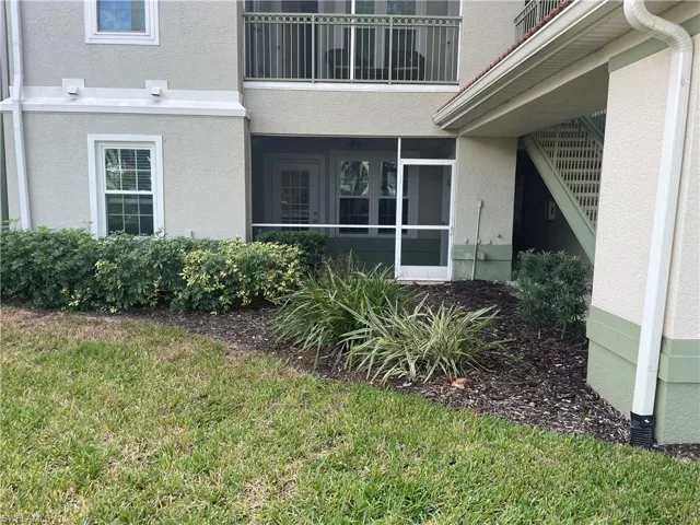 Entrance to property with a sunroom, stucco siding, and a lawn