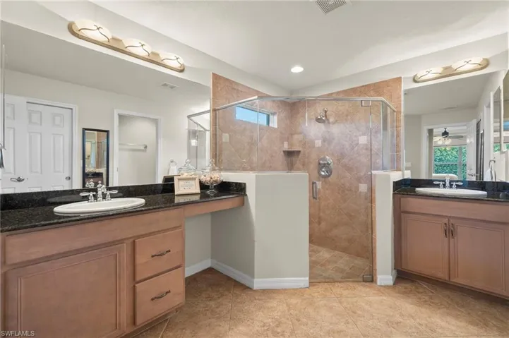 Bathroom with vanity, tile patterned floors, a shower with door, and ceiling fan