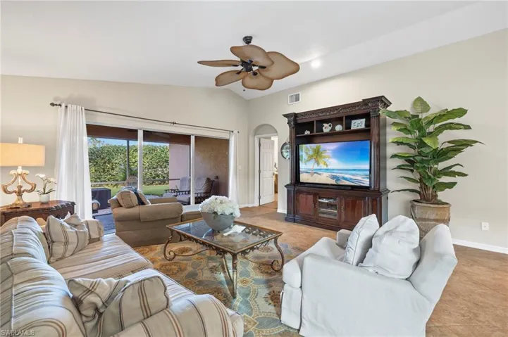 Living room featuring ceiling fan, lofted ceiling, and light tile patterned flooring