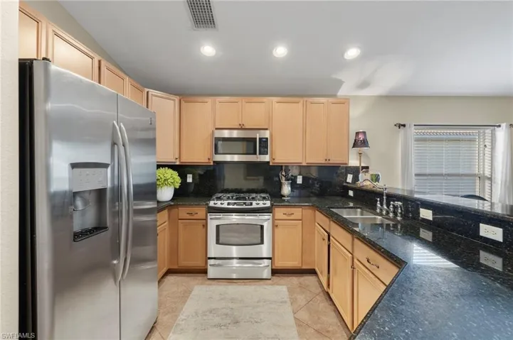 Kitchen featuring kitchen peninsula, sink, light brown cabinets, and appliances with stainless steel finishes