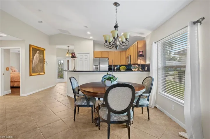 Dining space featuring a chandelier, light tile patterned flooring, and vaulted ceiling