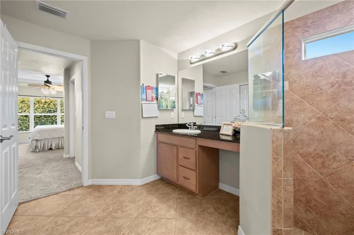 Bathroom with a textured ceiling, ceiling fan, walk in shower, and vanity