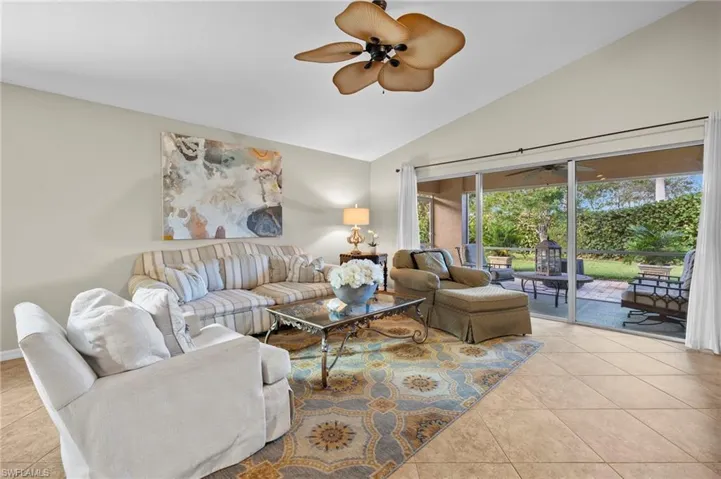 Living room featuring ceiling fan, light tile patterned flooring, and lofted ceiling