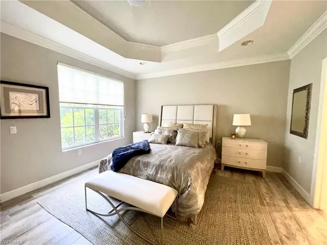 Bedroom featuring a tray ceiling, crown molding, wood finished floors, and recessed lighting