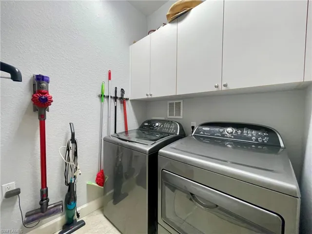 Laundry room featuring a textured wall, cabinet space, and separate washer and dryer
