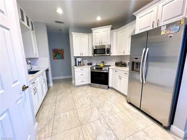 Kitchen featuring stainless steel appliances, white cabinetry, recessed lighting, and glass insert cabinets