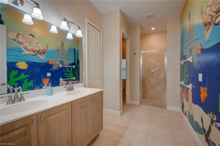 Full bath with a stall shower, double vanity, and light tile patterned floors