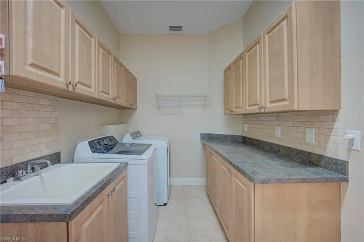 Laundry area with washer and dryer, cabinet space, and light tile patterned flooring