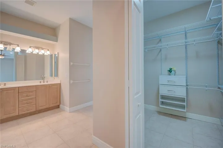 Bathroom featuring double vanity, light tile patterned flooring, and a spacious closet